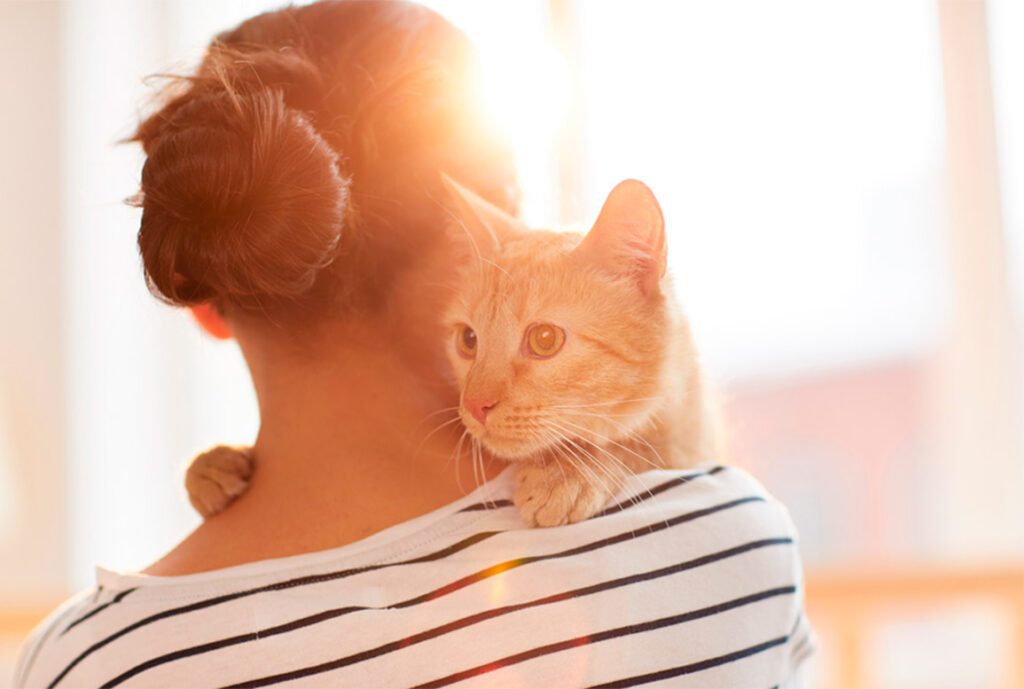 Mujer de espaldas con un gato sobre el hombro
